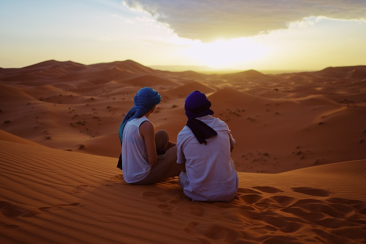 The Ultimate Moroccan Road Trip: From the Blue Streets of Chefchaouen to the Sahara Dunes 2025 two men sitting on sand dunes